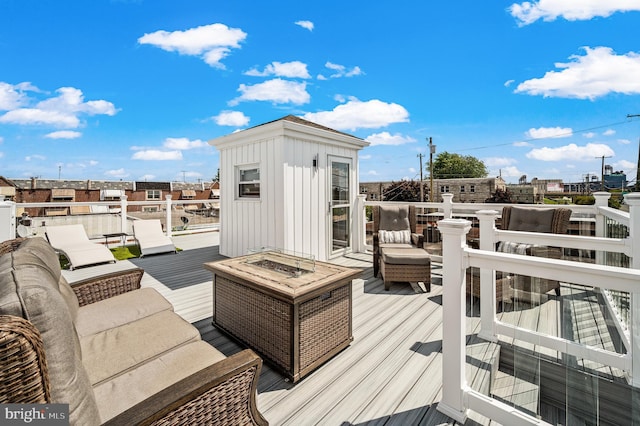 wooden deck featuring an outdoor living space with a fire pit