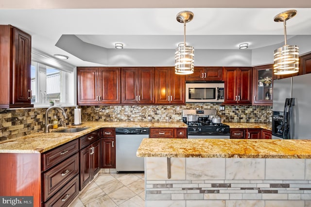 kitchen featuring appliances with stainless steel finishes, pendant lighting, tasteful backsplash, sink, and light stone counters