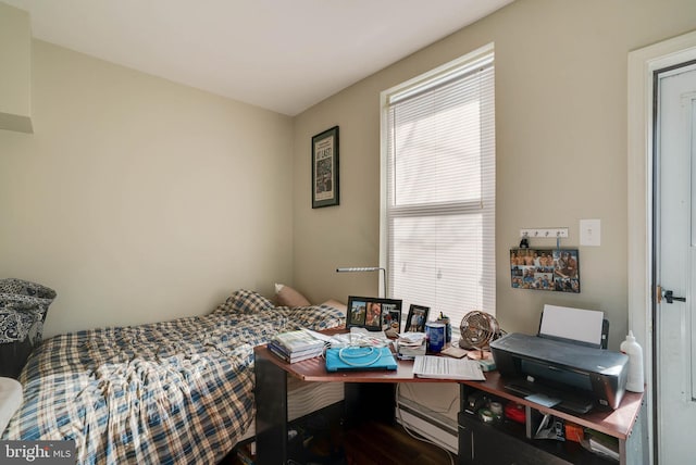 bedroom featuring a baseboard heating unit and wood-type flooring