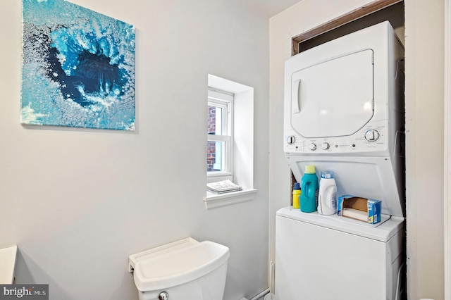 bathroom with stacked washer and dryer and toilet