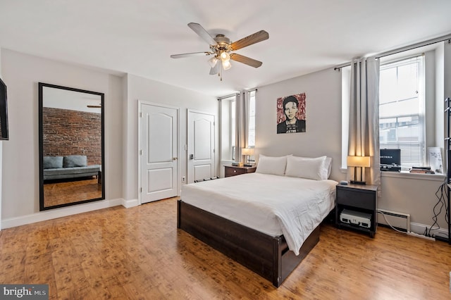 bedroom with light wood finished floors, a baseboard radiator, a ceiling fan, and baseboards