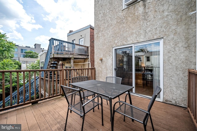 wooden terrace with outdoor dining space and stairway