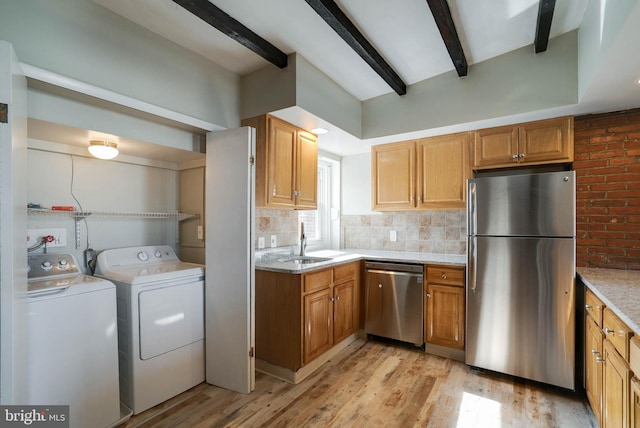 kitchen featuring appliances with stainless steel finishes, beam ceiling, light stone counters, light hardwood / wood-style floors, and independent washer and dryer