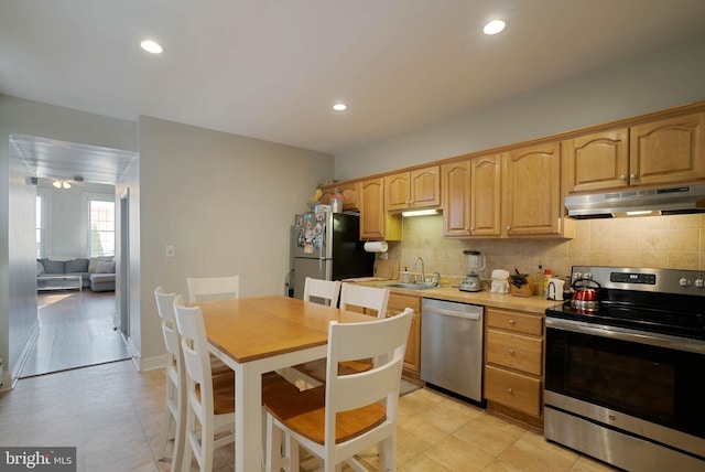 kitchen with appliances with stainless steel finishes, light brown cabinetry, light tile patterned floors, and backsplash