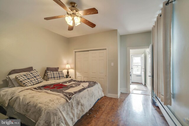 bedroom with ceiling fan, hardwood / wood-style flooring, a closet, and baseboard heating