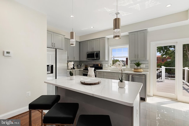 kitchen with light stone counters, baseboards, hanging light fixtures, appliances with stainless steel finishes, and tasteful backsplash