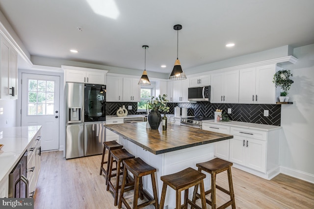 kitchen with a kitchen bar, plenty of natural light, stainless steel appliances, and butcher block countertops