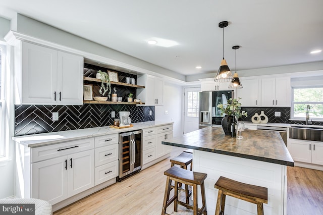 kitchen with beverage cooler, a kitchen island, and white cabinets