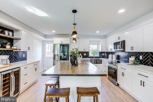 kitchen with a breakfast bar area, wine cooler, wood counters, a center island, and stainless steel appliances