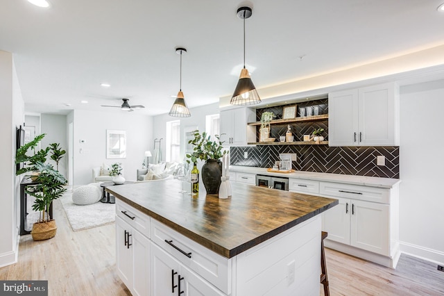 kitchen featuring light wood-type flooring, tasteful backsplash, wood counters, a kitchen island, and ceiling fan