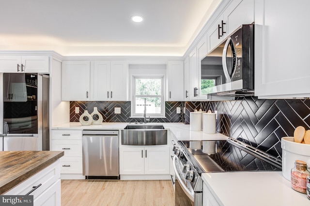 kitchen with backsplash, wood counters, appliances with stainless steel finishes, and white cabinetry