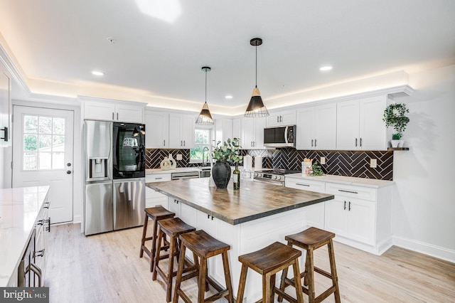 kitchen with wooden counters, a kitchen breakfast bar, stainless steel appliances, and backsplash