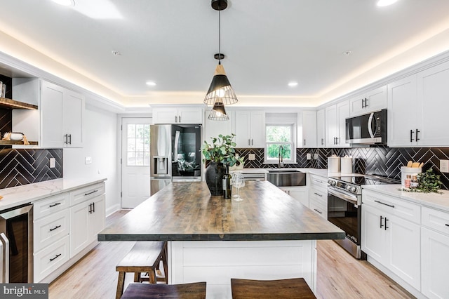 kitchen featuring backsplash, light wood-type flooring, appliances with stainless steel finishes, sink, and a kitchen island