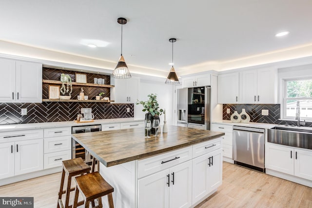 kitchen featuring a center island, wood counters, stainless steel appliances, wine cooler, and a breakfast bar