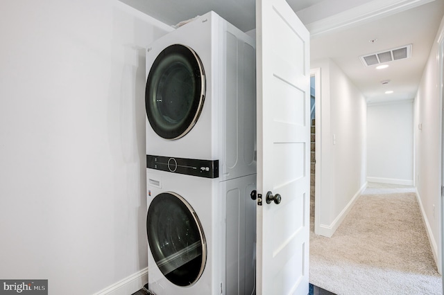 laundry area featuring light colored carpet and stacked washer / dryer