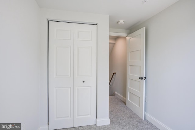 unfurnished bedroom featuring a closet and light colored carpet