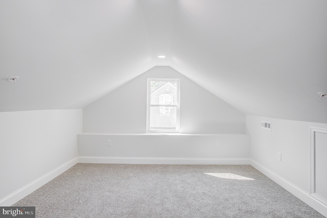 additional living space featuring lofted ceiling and light colored carpet