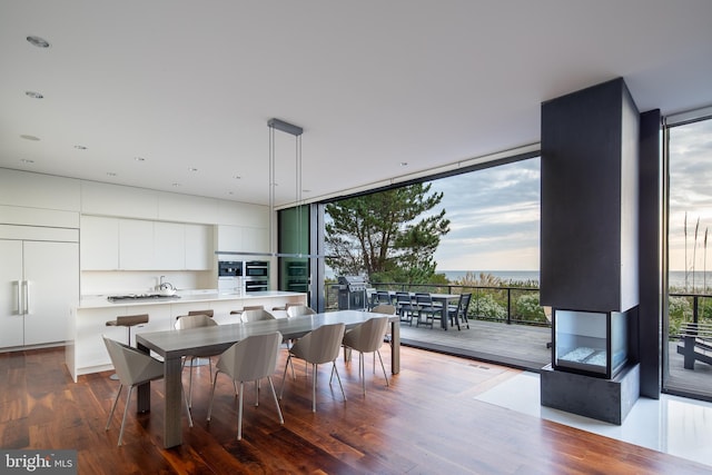 dining space with dark wood-type flooring, plenty of natural light, a water view, and floor to ceiling windows