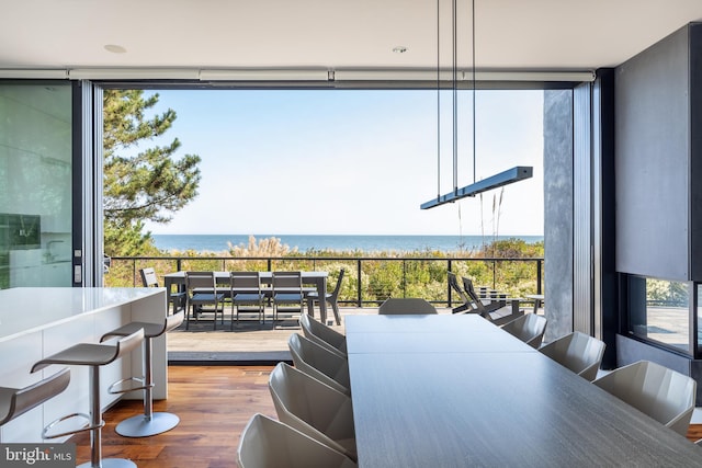 dining area with expansive windows, a water view, and wood finished floors