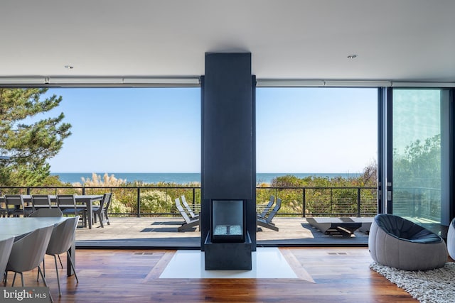 doorway to outside featuring floor to ceiling windows, a water view, and wood finished floors