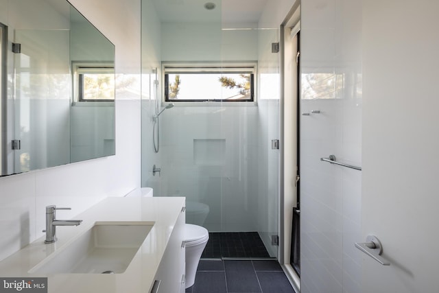 bathroom with tile walls, toilet, vanity, a shower stall, and tile patterned floors