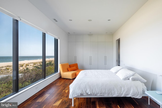 bedroom featuring a water view, a beach view, and wood finished floors