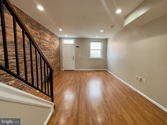 entryway with brick wall and light wood-type flooring