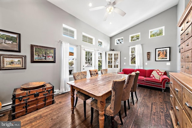 dining room with ceiling fan, high vaulted ceiling, a baseboard heating unit, and dark wood-type flooring