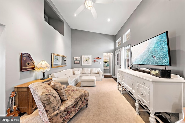 carpeted living room featuring ceiling fan and a high ceiling