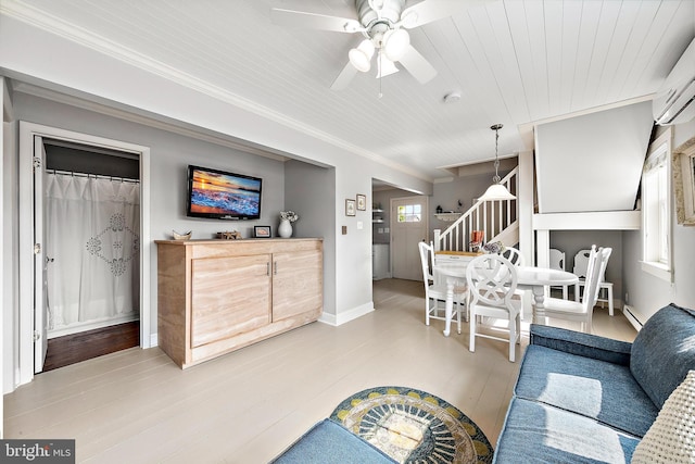 living room with ceiling fan, crown molding, a wall mounted AC, and light wood-type flooring