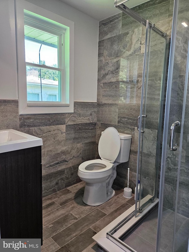 bathroom featuring tile walls, an enclosed shower, tile patterned flooring, vanity, and toilet