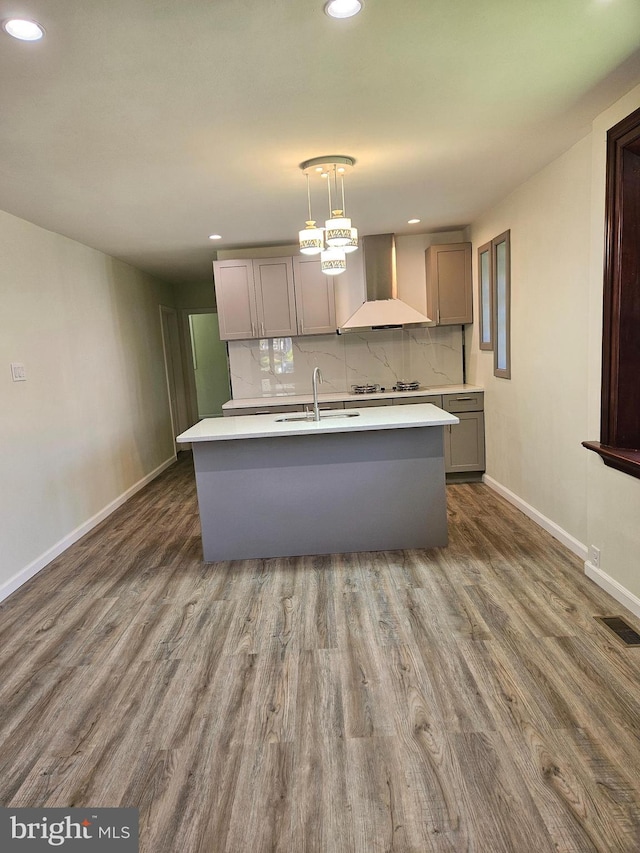 kitchen featuring wall chimney range hood, backsplash, dark hardwood / wood-style floors, pendant lighting, and gray cabinets