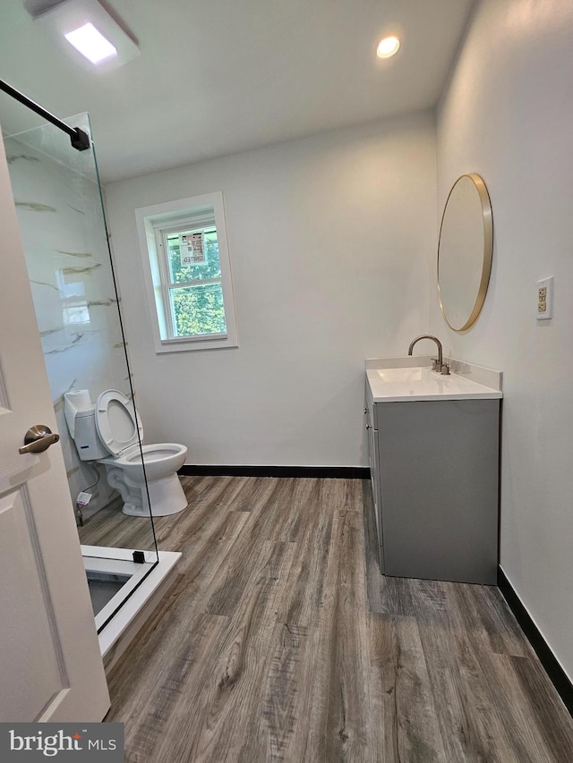 bathroom featuring toilet, a shower, hardwood / wood-style flooring, and vanity