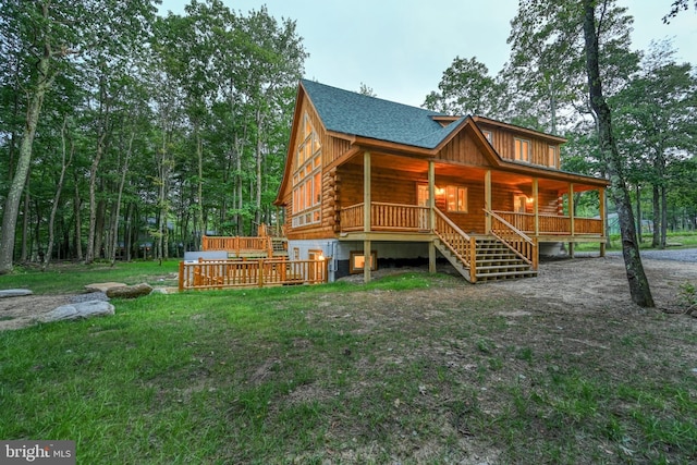 view of front of home with a porch, a front yard, log siding, and a shingled roof