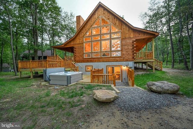 back of house featuring central AC, log siding, a wooden deck, a chimney, and a hot tub