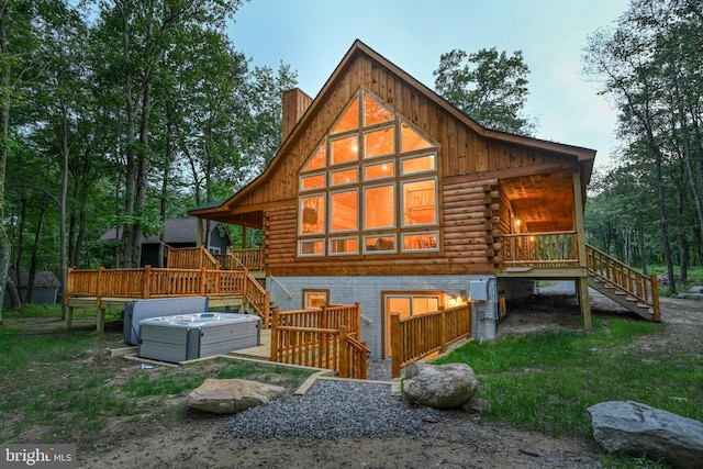 rear view of house with stairway, a chimney, log siding, and a hot tub