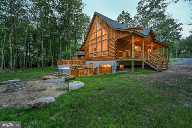 rear view of house featuring covered porch, stairway, a lawn, and log exterior