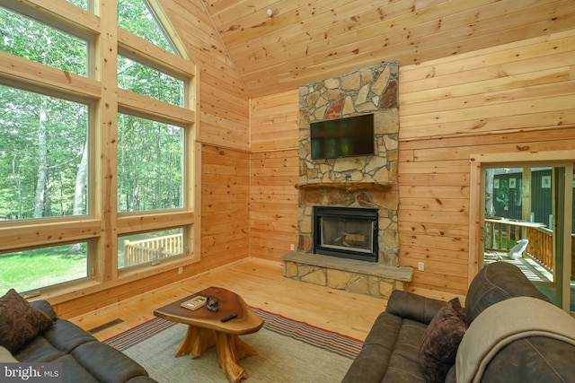 living room featuring wooden walls, high vaulted ceiling, a fireplace, and wood finished floors