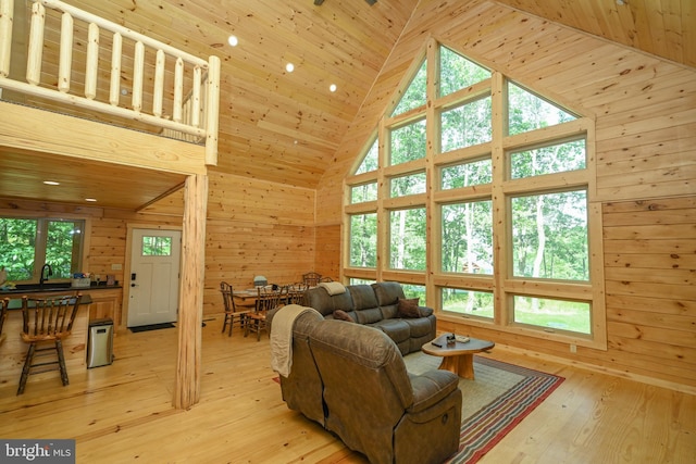 living area with light wood-type flooring, wood walls, wood ceiling, and high vaulted ceiling