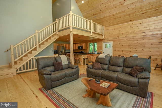 living area with wooden ceiling, stairway, light wood-type flooring, and a towering ceiling