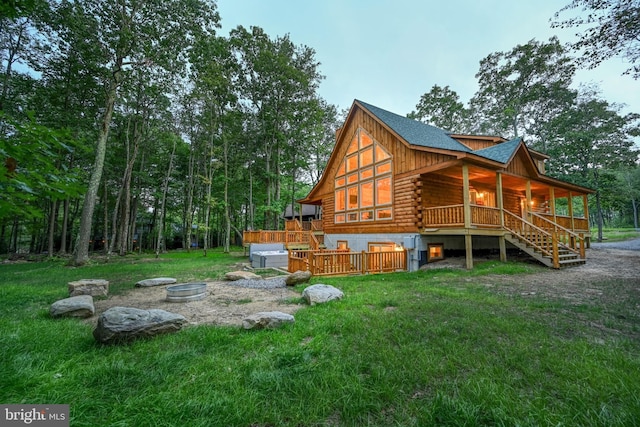 back of property with a fire pit, a yard, log siding, and stairs