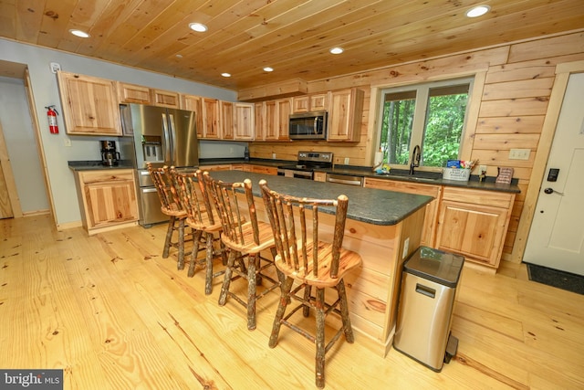 kitchen featuring stainless steel appliances, dark countertops, a kitchen island, and a kitchen breakfast bar