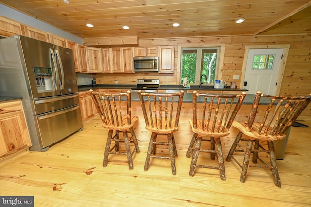 kitchen featuring wood ceiling, stainless steel appliances, and a kitchen breakfast bar