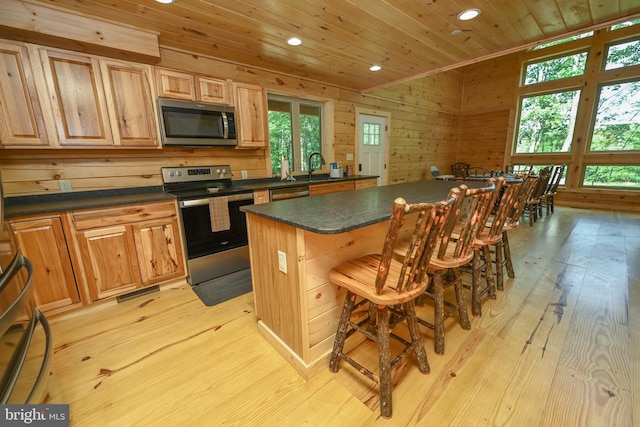 kitchen featuring dark countertops, wooden ceiling, a kitchen island, a breakfast bar area, and stainless steel appliances