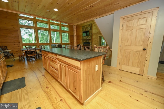 kitchen with dark countertops, wood walls, a kitchen island, and wooden ceiling