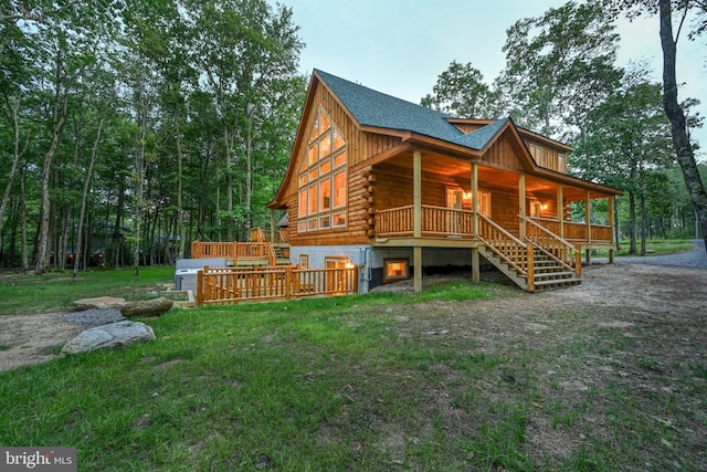 back of house with roof with shingles, a yard, covered porch, log siding, and stairs