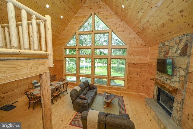 living room featuring wood ceiling, wood walls, plenty of natural light, and a stone fireplace