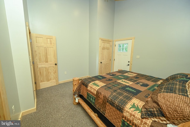 carpeted bedroom featuring baseboards and a high ceiling