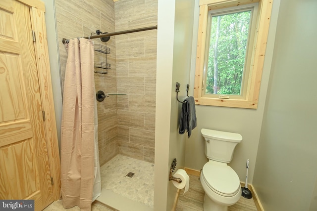 full bathroom with a stall shower, toilet, and baseboards