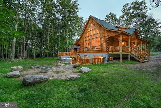 back of house featuring stairway, a jacuzzi, log siding, and a lawn